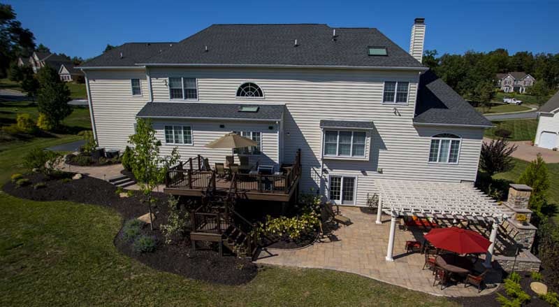 Expansive backyard with multi-level deck, pergola-covered patio, and stone hardscaping enhancing the landscape.