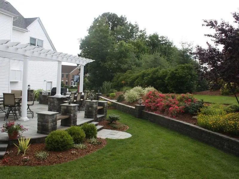 Backyard patio with stone seating area, pergola, and landscaped garden beds