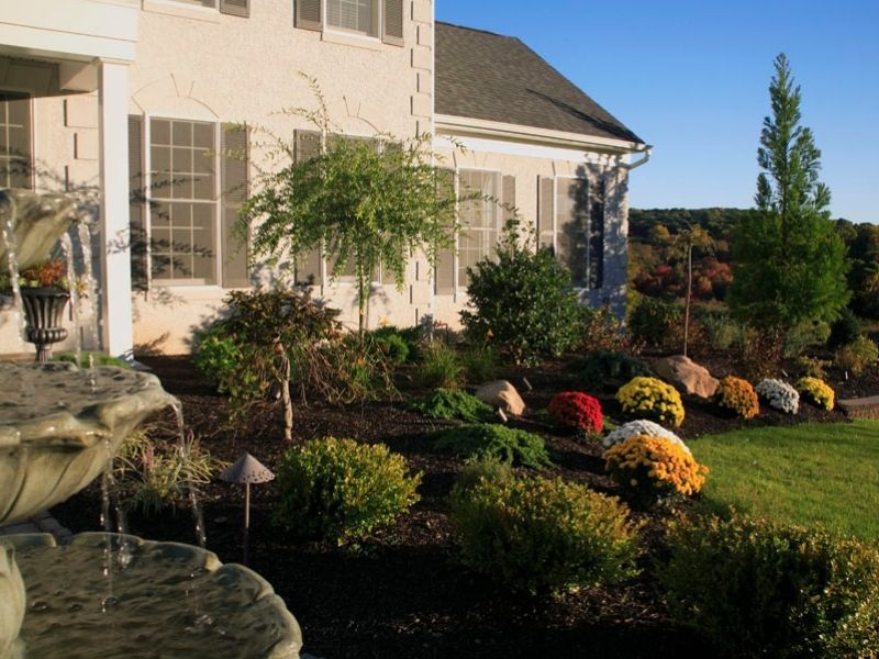 Colorful flower bed along stone retaining wall on paved patio