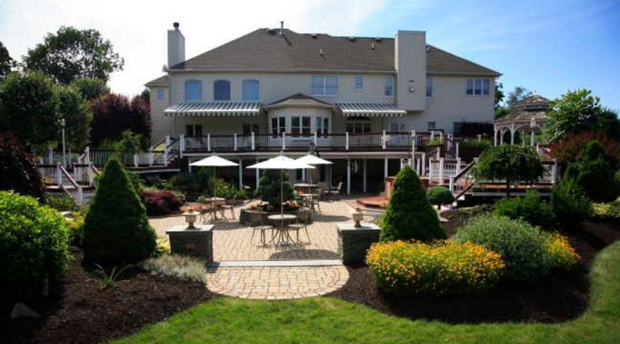 Landscaped backyard patio with seating, umbrellas, and garden beds